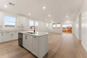 Kitchen with white cabinets, light wood-style floors, recessed lighting, a center island with sink, and stainless steel dishwasher