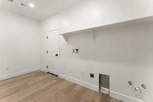 Laundry area with light wood-style floors, hookup for a washing machine, hookup for a gas dryer, electric dryer hookup, and recessed lighting