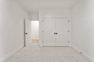 Unfurnished bedroom featuring light carpet and a closet