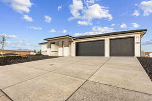 Prairie-style house with an attached garage, stucco siding, concrete driveway, and a tiled roof