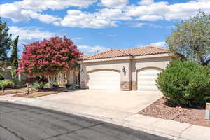 Mediterranean / spanish home with stone siding, stucco siding, an attached garage, driveway, and a tile roof