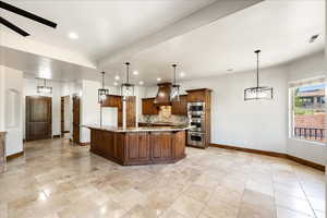 Kitchen featuring recessed lighting, custom exhaust hood, light stone countertops, a large island, and pendant lighting