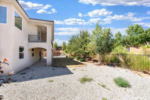 Fenced backyard featuring a balcony and a patio