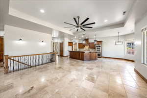 Kitchen with light countertops, a ceiling fan, open floor plan, recessed lighting, and an island with sink