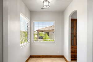 Empty room with arched walkways and light tile patterned floors