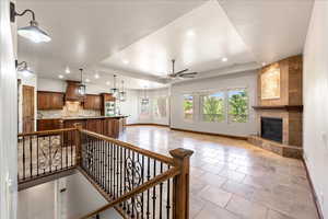 Living area featuring light tile patterned floors, a ceiling fan, a tile fireplace, recessed lighting, and a tray ceiling