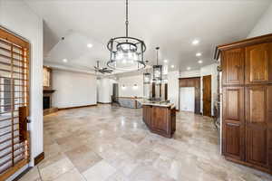 Kitchen with open floor plan, ceiling fan, light stone counters, a tiled fireplace, and pendant lighting