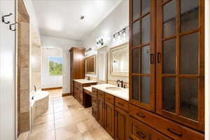 Bathroom with two vanities, a bath, and tile patterned floors