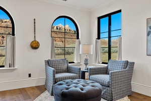 Sitting room with wood finished floors, crown molding, and healthy amount of natural light