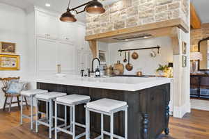 Kitchen with dark wood-style flooring, white cabinets, light countertops, and a breakfast bar