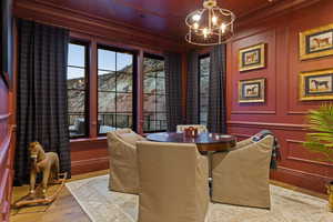 Dining space featuring a decorative wall, a chandelier, ornamental molding, wood finished floors, and a mountain view