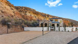 View of front of house with volleyball court, stone siding, and a mountain view