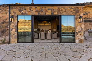 View of exterior entry with stone siding and a patio area