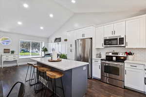 Kitchen with appliances with stainless steel finishes, dark wood-type flooring, tasteful backsplash, white cabinets, and recessed lighting
