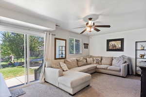 Carpeted living room featuring ceiling fan