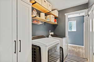 Laundry area featuring washing machine and clothes dryer, wood finished floors, and a textured ceiling