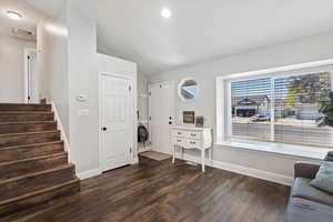 Entrance foyer featuring vaulted ceiling, dark wood finished floors, and stairs