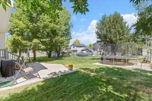 Fenced backyard featuring a trampoline and a patio area