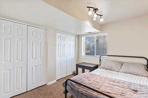 Bedroom featuring a textured ceiling, multiple closets, and carpet flooring