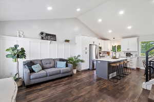 Living room featuring recessed lighting, dark wood-type flooring, and high vaulted ceiling