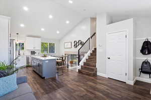 Kitchen featuring a kitchen bar, a kitchen island, dark wood-style flooring, white cabinets, and light countertops