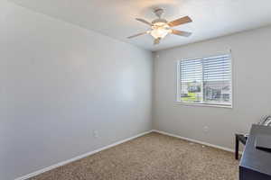 Unfurnished office with a textured ceiling, carpet, and a ceiling fan