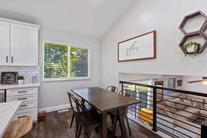 Dining room featuring plenty of natural light, vaulted ceiling, dark wood-type flooring, and ceiling fan