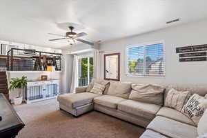 Carpeted living area with plenty of natural light, ceiling fan, and a textured ceiling
