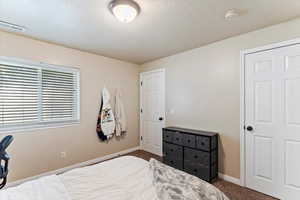 Bedroom with dark carpet and a textured ceiling