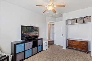 Carpeted bedroom with ceiling fan and a closet