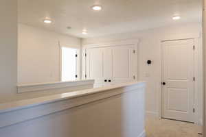 Hall with light carpet and recessed lighting