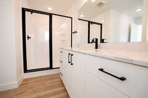 Full bathroom with vanity, a shower stall, wood finished floors, and recessed lighting
