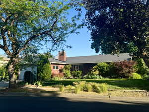 Ranch-style home with a chimney, a garage, and a front yard