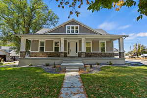 Craftsman-style home featuring stone siding, a porch, a front yard, and board and batten siding