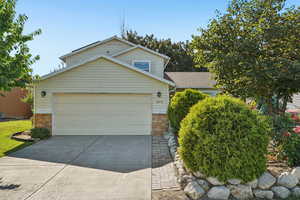 View of front of property featuring brick siding, concrete driveway, and an attached garage