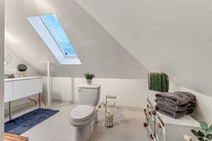 Bathroom with a skylight, lofted ceiling, vanity, and tile patterned floors
