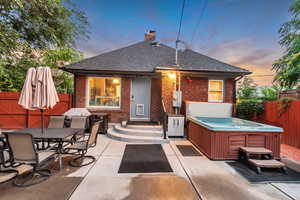 Rear view of property with a hot tub, brick siding, a patio, and a fenced backyard