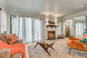 Living room with arched walkways, wood finished floors, and a lit fireplace