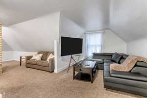 Carpeted living area with vaulted ceiling and baseboards