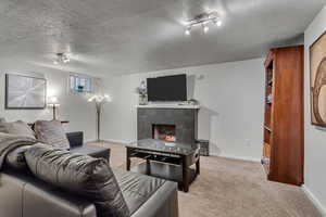 Living area featuring light carpet, a tile fireplace, and a textured ceiling
