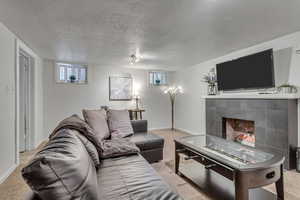 Living room featuring carpet flooring, a textured ceiling, and a fireplace