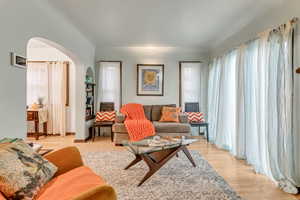 Living area featuring arched walkways and light wood finished floors
