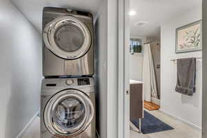 Laundry area featuring stacked washer and clothes dryer, light tile patterned floors, and recessed lighting