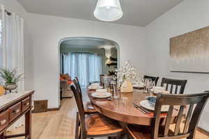Dining area with arched walkways and light wood-type flooring