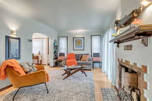 Living area with a fireplace with flush hearth, arched walkways, and light wood-style flooring