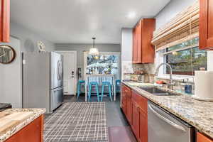Kitchen with appliances with stainless steel finishes, decorative backsplash, decorative light fixtures, light stone countertops, and recessed lighting