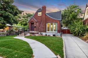 Tudor home featuring a chimney, brick siding, roof with shingles, and driveway