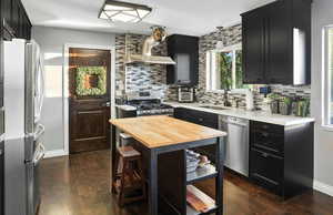 Kitchen with dark cabinets, wood counters, appliances with stainless steel finishes, and dark wood-type flooring