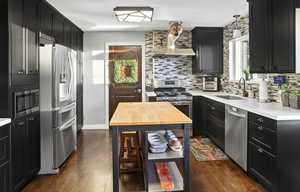 Kitchen featuring dark cabinetry, appliances with stainless steel finishes, and backsplash