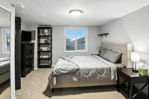Bedroom with a textured ceiling and light carpet
